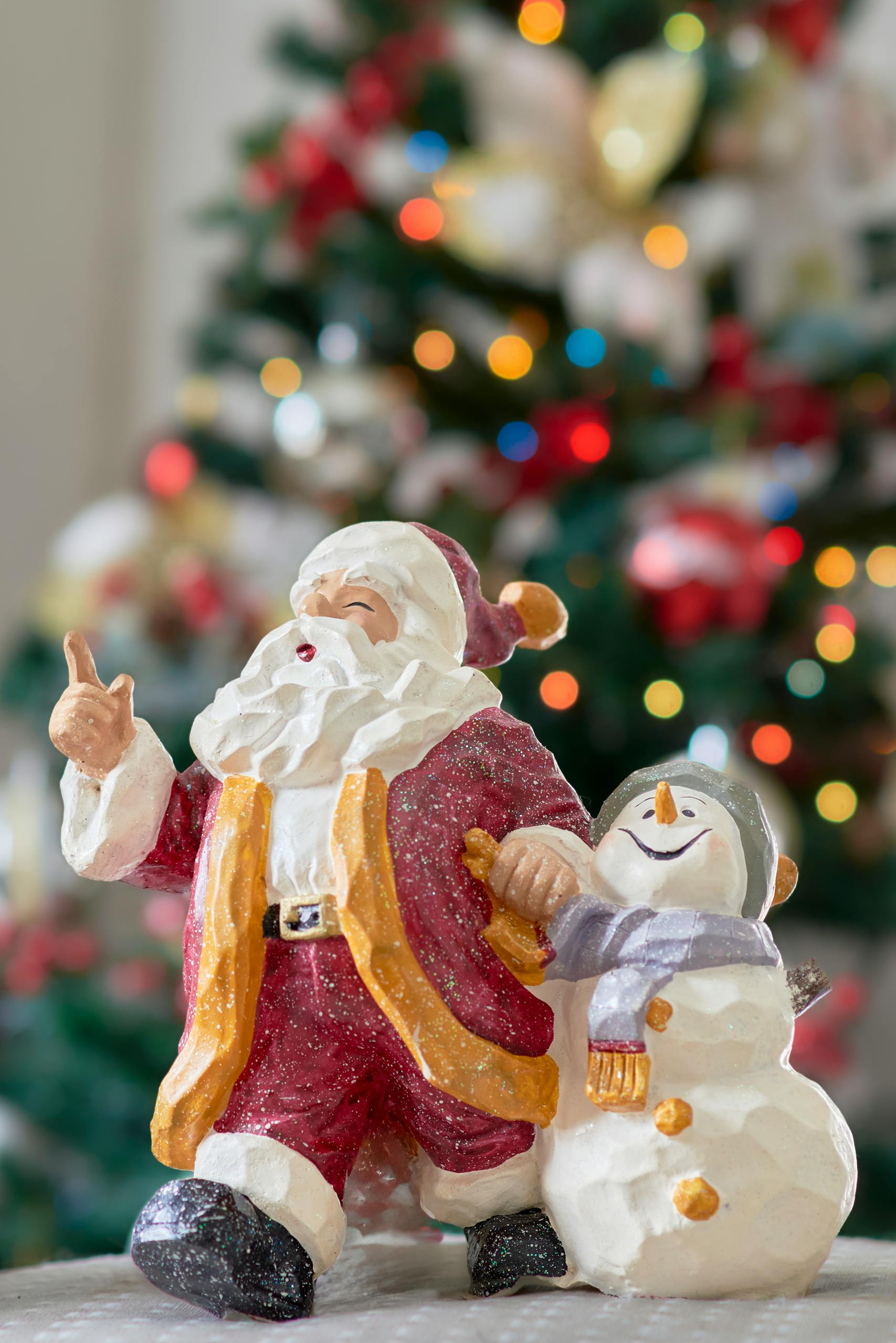 Colorful figurines of Santa and snowman with a holiday tree in the background.