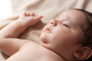 Gentle close-up portrait of a newborn baby lying down, capturing innocence and tranquility.