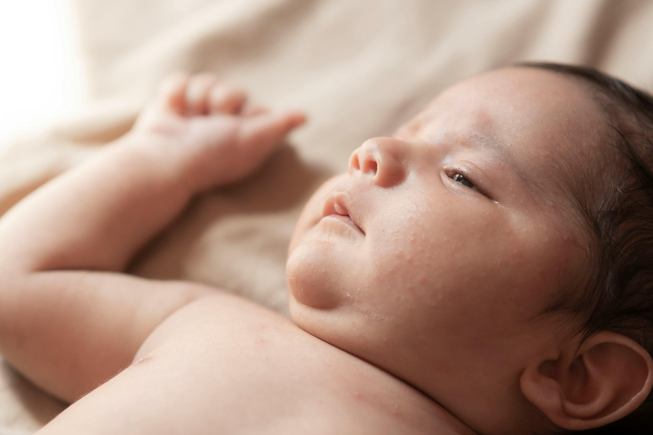 Gentle close-up portrait of a newborn baby lying down, capturing innocence and tranquility.