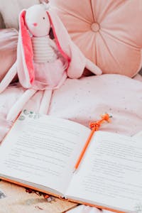 Pink-themed cozy bedroom setup with a stuffed toy, open book, and cute decor.