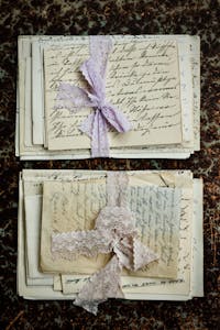 Stacked vintage handwritten letters tied with lace on a textured surface.